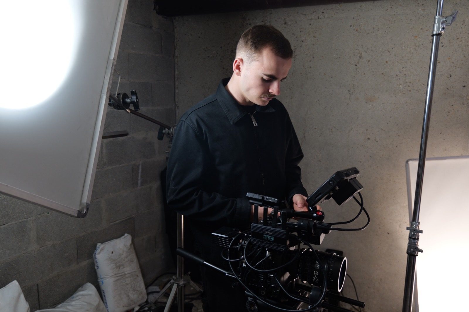 François Beaudoin règle le moniteur d’une caméra cinéma entre deux projecteurs, dans un studio aux murs de béton