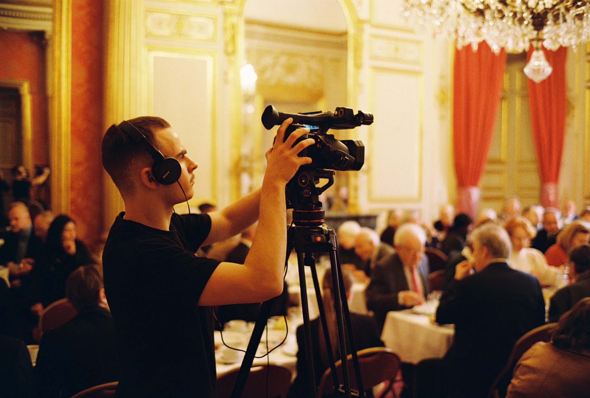 François Beaudoin au cadrage, caméra sur trépied et casque sur les oreilles, pendant un tournage au Sénat, Paris, en 2025